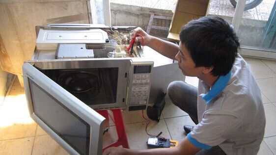Nhân viên Điện Lạnh đang sửa chữa lò vi sóng tại nhà Gò Vấp